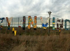 Art installation featuring letters on a chain-link fence